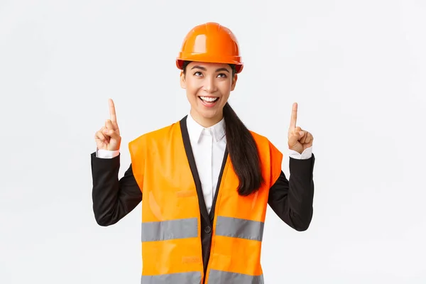 Bâtiment, construction et concept industriel. Succès heureux asiatique femme ingénieur dans casque de sécurité inspecter objet, regarder et pointant les doigts vers le haut satisfait. Architecte satisfait du bon résultat — Photo