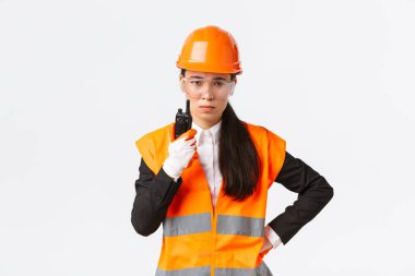 Hayal kırıklığına uğramış Asyalı kadın inşaat mühendisi, güvenlik üniformalı teknisyen ya da endüstri müdürü telsizle çalışanı arıyor, şirkette radyo iletişimini kullanarak kişisel olarak azarlıyor.