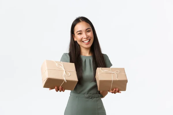 Sonriendo propietario exitoso de la pequeña empresa que trabaja desde casa con productos hechos a mano, embalaje de artículos de entrega en cajas, la celebración de paquetes listos para el envío a los clientes, de pie fondo blanco —  Fotos de Stock