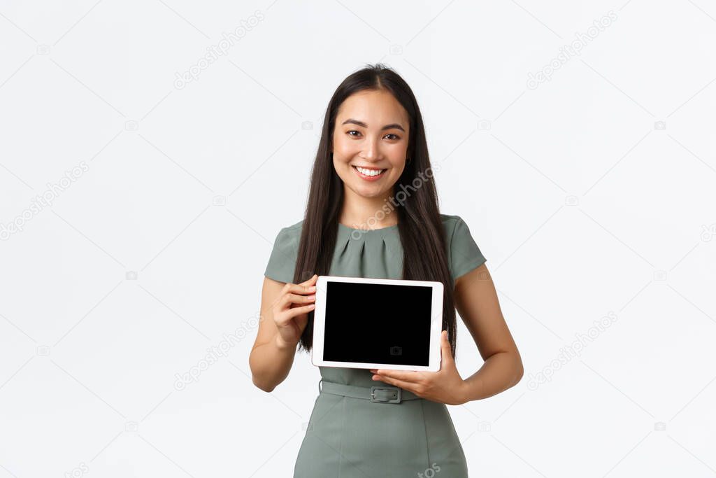 Small business owners, startup and work from home concept. Smiling attractive asian woman introduce her online store, showing application on digital tablet screen, making presentation