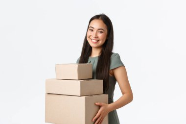 Küçük işletme sahipleri, ev kavramından başlayarak ve çalışarak. Gülümseyen genç mağaza müdürü, Asyalı iş kadını paketleri toplar, siparişleri kutulara koyar ve teslimat şirketine taşır.