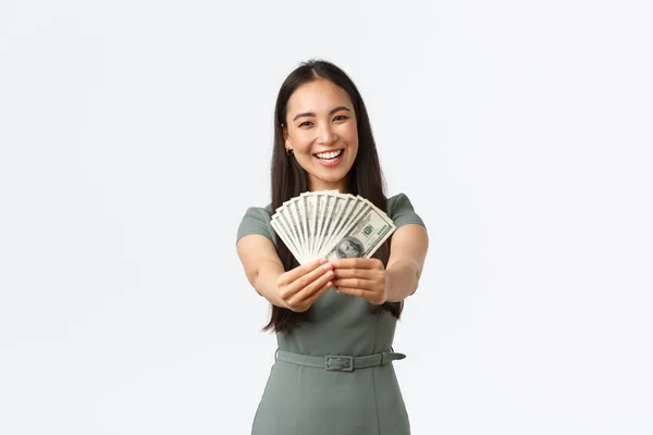 Glad leende asiatisk kvinnlig företagare, butikschef visar pengar hon tjänat på online-butik, håller kontanter och glädje, visa upp med sin inkomst, stående vit bakgrund — Stockfoto