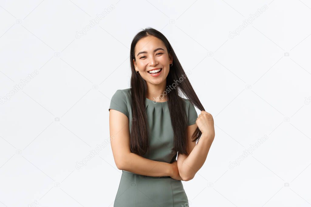 Small business owners, women entrepreneurs concept. Carefree smiling businesswoman, asian female in dress touching hair and laughing, having coquettish conversation, white background