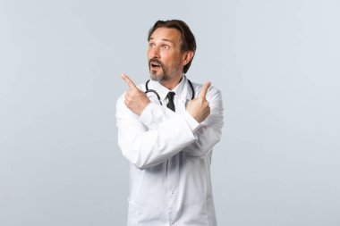 Covid-19, koronavirüs salgını, sağlık çalışanları ve pandemik konsept. Beyaz önlüklü kararsız doktor, parmaklarını yana doğru gösteriyor ve değişkenlere bakıyor, seçim yapıyor.