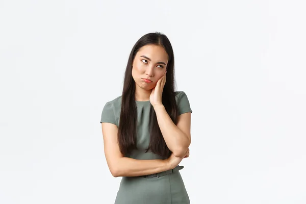 Small business owners, women entrepreneurs concept. Annoyed or bored, reluctant asian woman sitting on boring meeting, roll eyes and pouting with indifferent face, standing white background — Stock Photo, Image