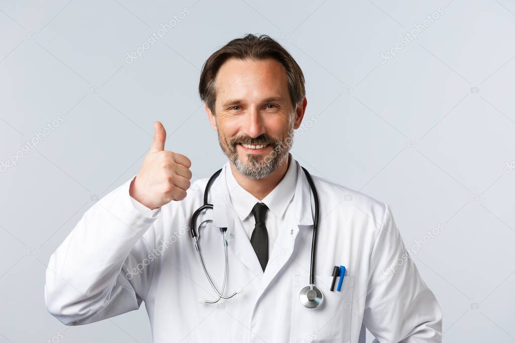 Covid-19, preventing virus, healthcare workers and vaccination concept. Close-up of satisfied and pleased doctor in white coat, show thumb-up in approval, recommend medical product or clinic service