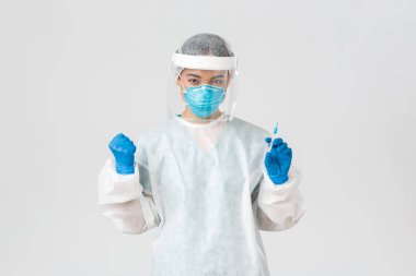 Covid-19, koronavirüs hastalığı, sağlık çalışanları konsepti. Kararlı ve kendinden emin Asyalı kadın doktor, teknoloji laboratuarı çalışanı kişisel koruyucu ekipman elinde aşı şırıngası tutuyor.