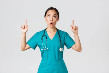 Covid-19, sağlık çalışanları, salgın konsepti. Etkilendim ve büyülendim. Güzel Asyalı kadın hemşire, önlüklü doktor çenesini indirip yukarı bakıyor, hayret içinde kalıyorum.