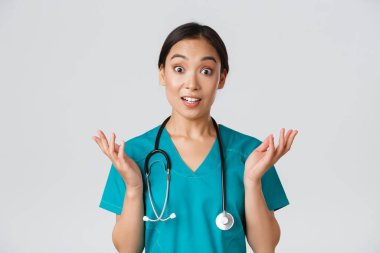 Sağlık çalışanları, virüsü önleme, karantina kampanyası konsepti. Şaşırmış ve eğlenmiş, mutlu Asyalı kadın hemşire, doktor harika haberler duyup, ellerini kaldırıp kameraya bak.
