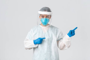 Covid-19, koronavirüs hastalığı, sağlık çalışanları konsepti. Profesyonel kadın doktor, teknoloji laboratuarı çalışanı kişisel koruma ekipmanlarında parmak gösteren, yol gösteren, beyaz arka plan