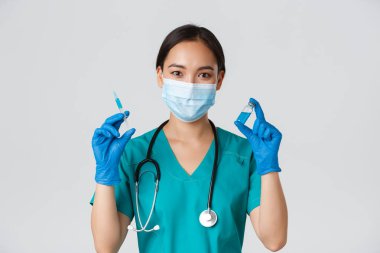 Covid-19, koronavirüs hastalığı, sağlık çalışanları konsepti. Yakışıklı, gülümseyen Asyalı kadın hemşire, aşı ampul ve şırınga gösteren doktor, enjeksiyona hazır olun, beyaz arka plan.