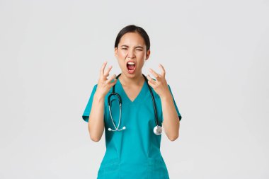 Covid-19, healthcare workers and preventing virus concept. Angry pissed-off asian female nurse, doctor losing temper, stressed-out physician shouting in anger, looking mad and aggressive