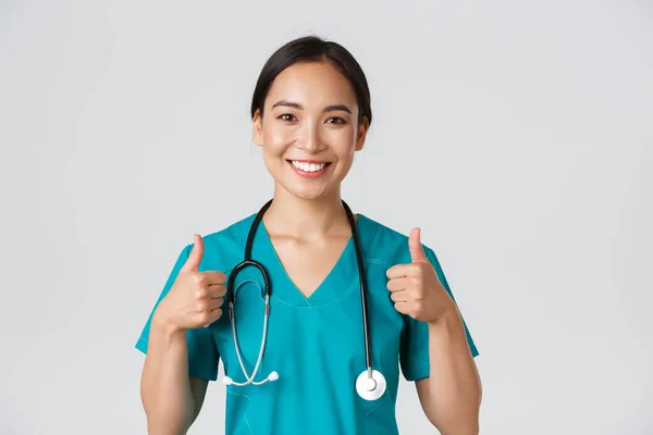 Healthcare workers, preventing virus, quarantine campaign concept. Close-up of upbeat smiling asian doctor, physician looking confident, ensure patient, showing thumbs-up in approval — Stock Photo, Image