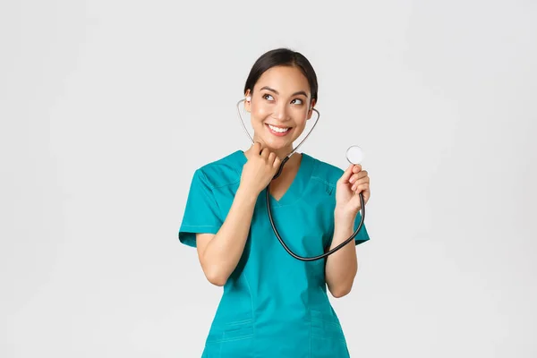 Covid-19, healthcare workers and preventing virus concept. Smiling cute asian doctor, female nurse examine patient lungs, using stethoscope, listening closer, standing white background — Stock Photo, Image