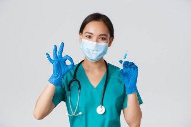Covid-19, koronavirüs hastalığı, sağlık çalışanları konsepti. Yakışıklı Asyalı kadın doktor, tıbbi maske ve lastik eldiven giyen doktor iyi niyet göstergesi ve aşı ile şırınga, beyaz arka plan