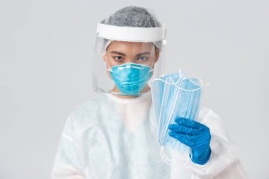 Covid-19, koronavirüs hastalığı, sağlık çalışanları konsepti. Kişisel koruma ekipmanları içinde kendine güvenen ciddi görünümlü Asyalı kadın doktor hastanın tıbbi maske takıp beyaz arka plan giymesinde ısrar ediyor.