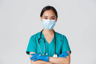 Covid-19, koronavirüs hastalığı, sağlık çalışanları konsepti. Kendine güvenen, gülümseyen, profesyonel Asyalı doktor, tıbbi maskeli hemşire ve lastik eldivenler muayene için hazır, beyaz arka plan.