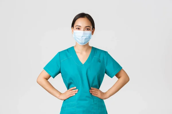 Covid-19, onemocnění koronavirem, koncept zdravotnických pracovníků. Veselá usměvavá asijská doktorka, lékařka v pláštích a lékařské masce, vypadá optimisticky, pracuje s pacienty v nemocnici — Stock fotografie