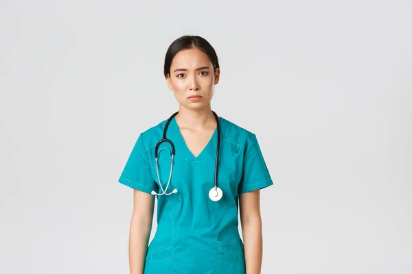 Covid-19, personnel de santé, concept pandémique. Jeune infirmière asiatique épuisée, médecin fatigué après le quart de travail à l'hôpital, triste avec la fatigue, debout fond blanc dans les blouses — Photo