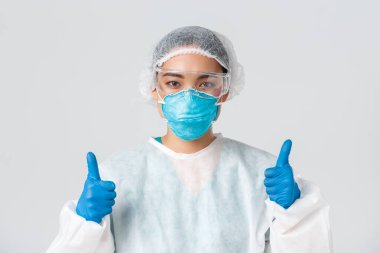 Covid-19, koronavirüs hastalığı, sağlık çalışanları konsepti. Kendine güvenen profesyonel Asyalı doktor, teknoloji laboratuarı çalışanı kişisel koruma ekipmanları onaylandı.