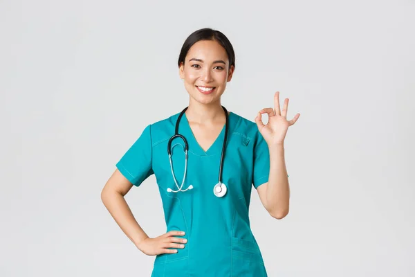 Covid-19, pracownicy służby zdrowia, koncepcja pandemii. Profesjonalny pewny siebie uśmiechnięty azjatycki kobieta lekarz, kobieta pielęgniarka w fartuch zapewnić wszystko pod kontrolą, pokazując okay gest zadowolony — Zdjęcie stockowe