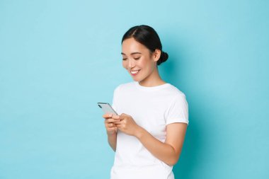 Yaşam tarzı, teknoloji ve e-ticaret konsepti. Çekici Asyalı kızın cep telefonu kullanışının, mesajlaşmasının, mesajlaşmasının ya da arkadaşlarıyla internet üzerinden sohbet etmesinin, akıllı telefon ekranına bakmasının