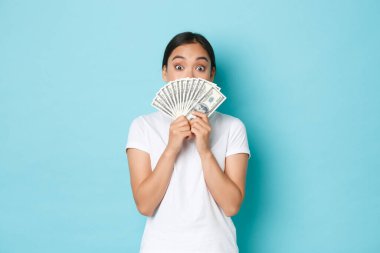 Alışveriş, para ve finans konsepti. Heyecanlı ve eğlenceli Asyalı kız dolarlarını internetten konser ya da harika bir ürün almak için hazırladı.