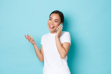 Yaşam tarzı, insanlar ve güzellik konsepti. Genç ve çekici bir kız bir şeyleri tartışıyor, neşeli sohbetler ediyor, cep telefonuyla konuşuyor, el kol hareketi yapıyor, neşeli gülüyor.