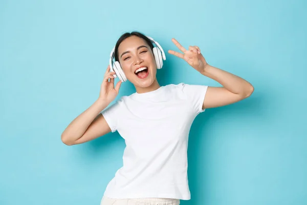 Concepto de compras, dinero y finanzas. Upbeat chica asiática en blanco casual camiseta, cantando karaoke, reproducción de música aplicación, escuchar música en auriculares inalámbricos y disfrutar de un sonido perfecto — Foto de Stock