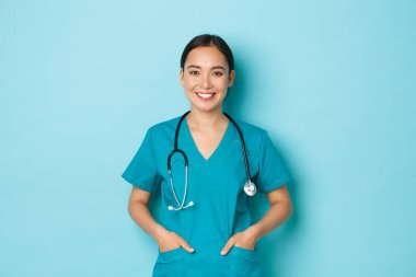 Covid-19, sosyal uzaklık ve koronavirüs salgını konsepti. Profesyonel doktorların yakın çekimi, hemşire ya da hekim olarak çalışan kadın önlük giyiyor, el ele tutuşuyor ve geniş bir gülümsemeyle gülümsüyor.
