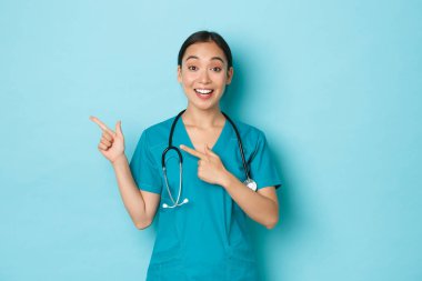 Covid-19, sosyal uzaklık ve koronavirüs salgını konsepti. Profesyonel doktor, kadın hemşire ya da doktor hastaları bilgilendirir. Sol üst köşeyi işaret ederek klinik afişini gösterir..