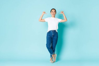 Fashion, beauty and lifestyle concept. Sassy attractive asian girl in casual clothes, pointing at herself, being professional, praising own accomplishment, show-off over light blue background clipart