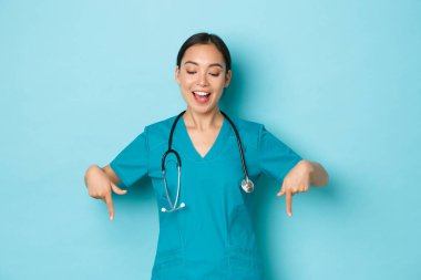 Covid-19, sosyal uzaklık ve koronavirüs salgını konsepti. Neşeli gülümseyen Asyalı kadın doktor, laboratuarda ya da klinikte hemşire, önlüklü, parmakla gösterip reklamlara bakıyor.