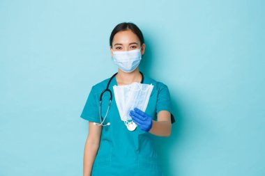 Covid-19, sosyal uzaklık ve koronavirüs salgını konsepti. Dost canlısı sevimli Asyalı kadın doktor, hastalara tıbbi maske veren hemşire, salgından korunmak için önleyici önlemler alınmasını tavsiye ediyor.