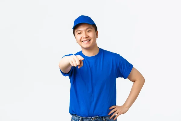 Alegre amigável ásia courier com aparelho, vestindo azul uniforme, procurando funcionários para a empresa, apontando dedo para a câmera como escolher você, escolher alguém, pé branco fundo — Fotografia de Stock