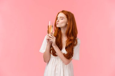 Sarhoş ve kaygısız, yakışıklı, neşeli ve mutlu bir kadın. Bardağı şampanyayla öperken sarhoş olmuş, partide çok alkol içmiş, pembe arka planda rahatlamış.