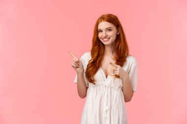 Bel yukarı portresi güzel Avrupalı, beyaz, moda elbiseli, üst sol köşesini gösteren kızıl saçlı kadın, davet gel ve çıkış promosyonu, tavsiye ver, pembe arka plan