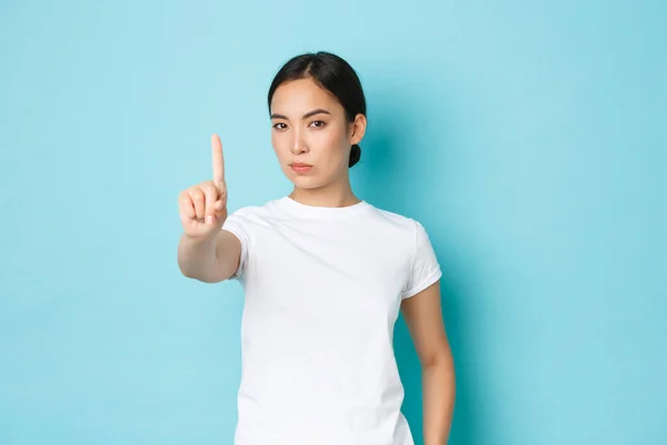 Serieus ogende assertieve jonge aziatische vrouw verbiedt actie, uiten sterke afkeuring of oneens, schudden vinger in waarschuwingsteken, verbieden iets slechts, kijken ontevreden en zelfverzekerd — Stockfoto