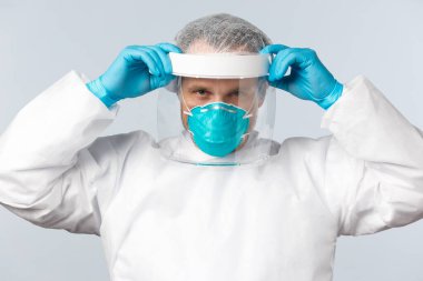 Covid-19, virüs, sağlık çalışanları ve aşı konsepti. Korunma ekipmanlarında uzman doktor. Coronavirus hastalığı üzerinde çalışırken yüz kalkanı ve solunum cihazı takın.
