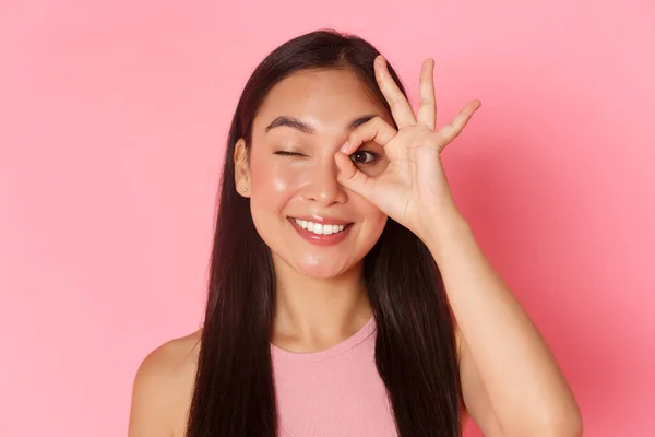 Concepto de belleza, moda y estilo de vida. Retrato de kawaii atractiva chica asiática mostrando buen gesto sobre el ojo y guiño despreocupado en la cámara, sonriendo complacido, garantía de calidad, recomendar lugar —  Fotos de Stock