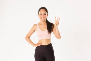 Spor, refah ve aktif yaşam tarzı konsepti. Gülümseyen sporcu, Asyalı fitness kızı kilo vermek ya da kas kazanmak için üç faydalı egzersiz gösteriyor.