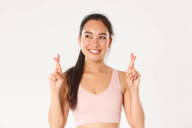 Spor, refah ve aktif yaşam tarzı konsepti. Yarışmayı kazanmak isteyen umut verici gülümseyen Asyalı sporcunun yakın çekimi, spor giyerken şans dilemek ve şans dilemek için dua ediyor.