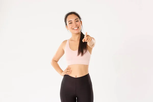 Sport, benessere e stile di vita attivo. Ritratto di allegra ed entusiasta asiatica donna fitness intrusore, membro della palestra in activewear invitante per l'allenamento, indicando fotocamera e sorridente — Foto Stock