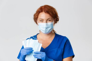 Tıp çalışanları, covid-19 salgını, koronavirüs konsepti. Gülümseyen şefkatli kadın hemşireye yakın çekim, lastik eldivenli doktor yüz maskesi ve sosyal mesafeyi kullanın, temel tavsiyeleri açıklayın