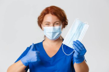 Tıp çalışanları, covid-19 salgını, koronavirüs konsepti. Profesyonel kadın hemşireye yakın çekim, doktor virüs salgınını önlemek için yüz maskesi takmayı ve ekipmanları korumayı öneriyor.