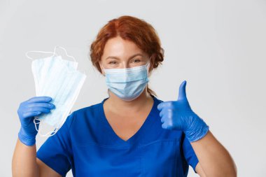 Tıp çalışanları, covid-19 salgını, koronavirüs konsepti. Profesyonel kadın hemşireye yakın çekim, doktor virüs salgınını önlemek için yüz maskesi takmayı ve ekipmanları korumayı öneriyor.
