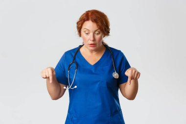 Tıp, sağlık ve koronavirüs konsepti. Etkileyici dilsiz, orta yaşlı doktor, mavi önlüklü bayan hemşire heyecanla bakıyor ve işaret ediyor, çene sallıyor ve nefes nefese kalıyordu.