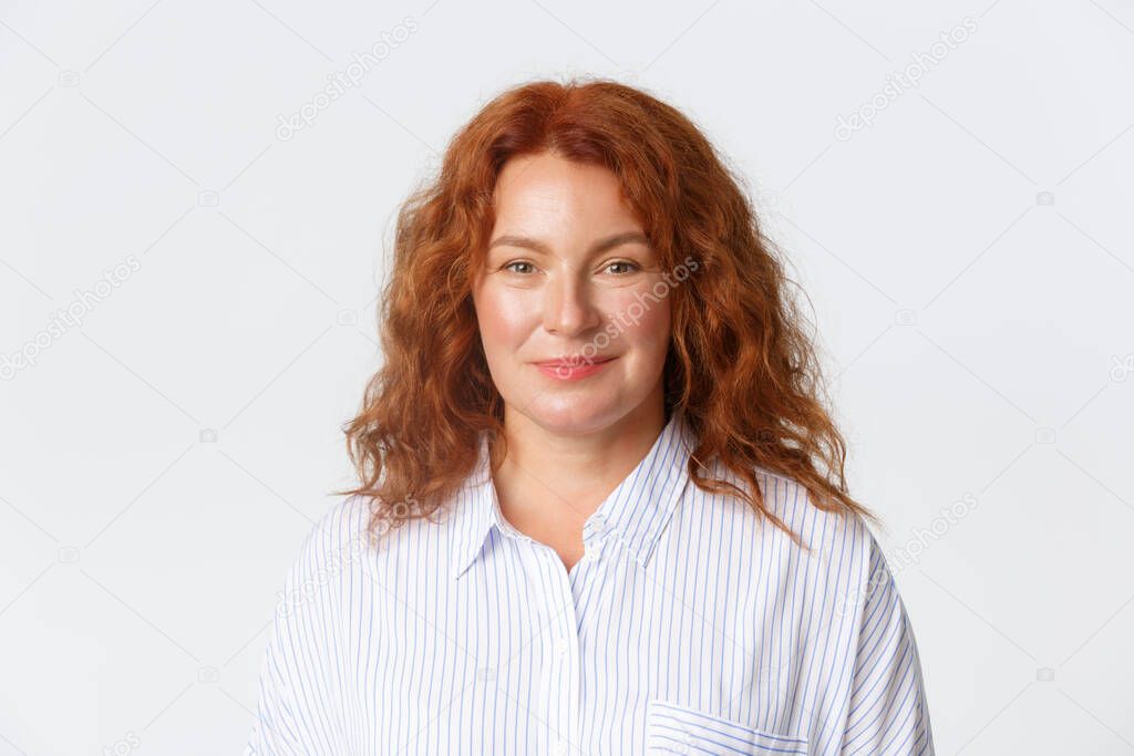 People, emotions and lifestyle concept. Close-up of smiling kind looking redhead woman in blouse standing over white background, gazing at camera hopeful and happy
