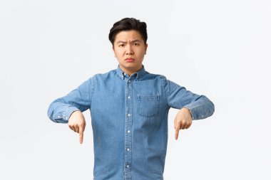 Hayal kırıklığına uğramış ve üzgün Asyalı genç adam şikayetçi, endişeli ve hoşnutsuz görünüyor. Mavi gömlekli adam işaret ediyor, duyuru yapıyor, rahatsız edici haberlere dikkat çekiyor.