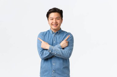 Gülümseyen neşeli Asyalı adam duyuru yapıyor. Sağ ve sol varyantları işaret eden adam, birkaç seçenek gösteriyor, mağazaları öneriyor, beyaz arka planda duruyor